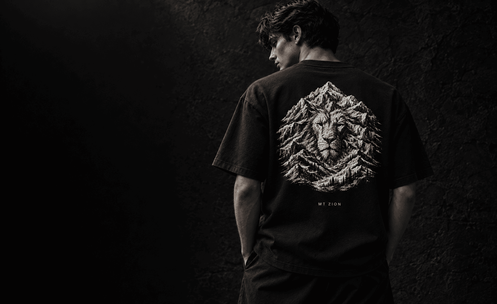 Generated campaign visualization of a model wearing the black LAMB / MOUNTAIN tee from behind, showing the complete Lion and Mount Zion artwork.
